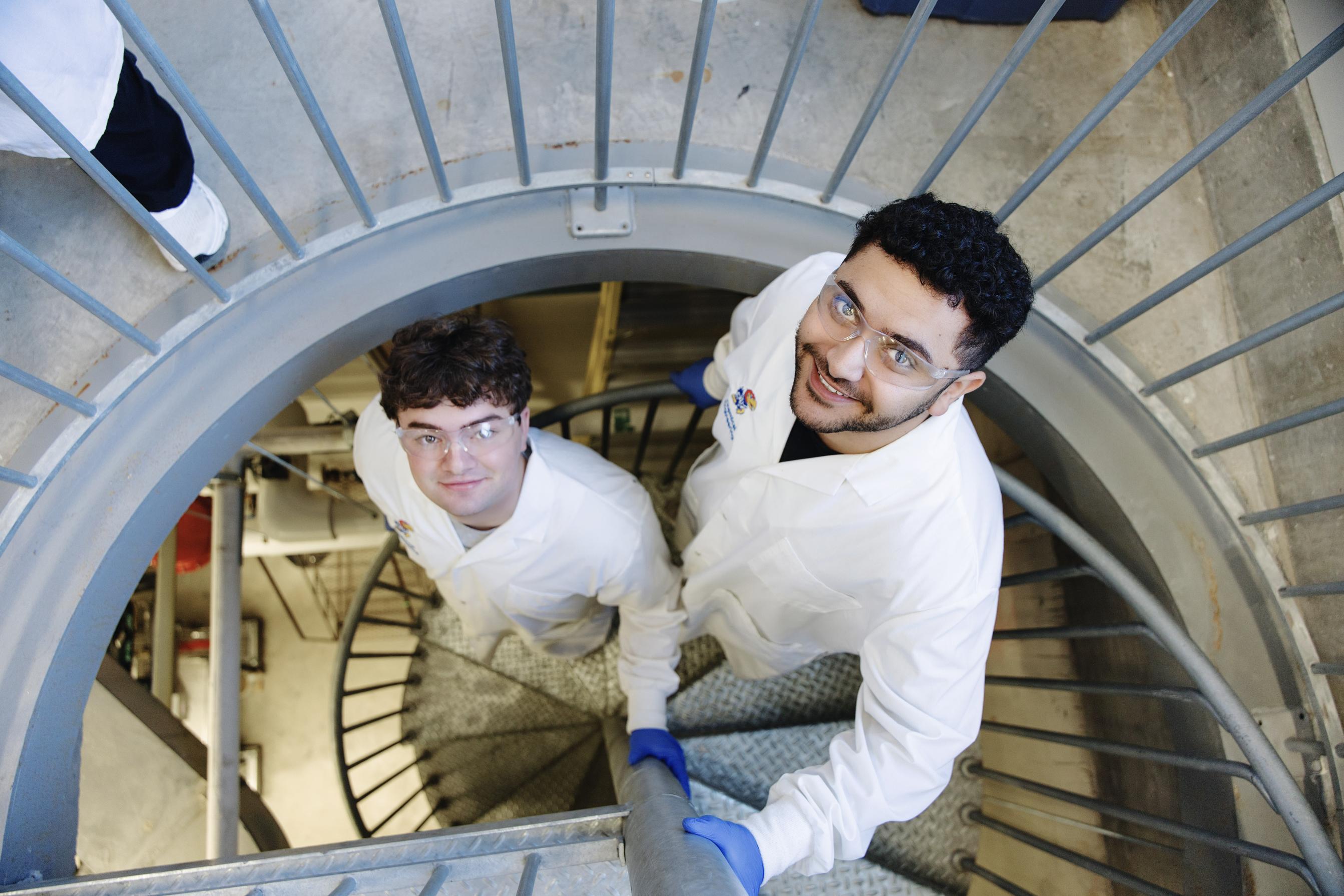 Two students looking up through a staircase by the distiallation tower