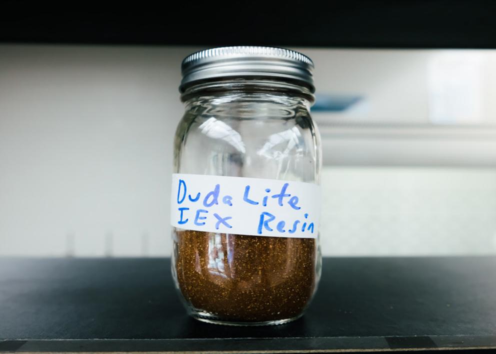 a mason jar labeled with the words Duda Lite IEX Resin and contains a dirt looking substance
