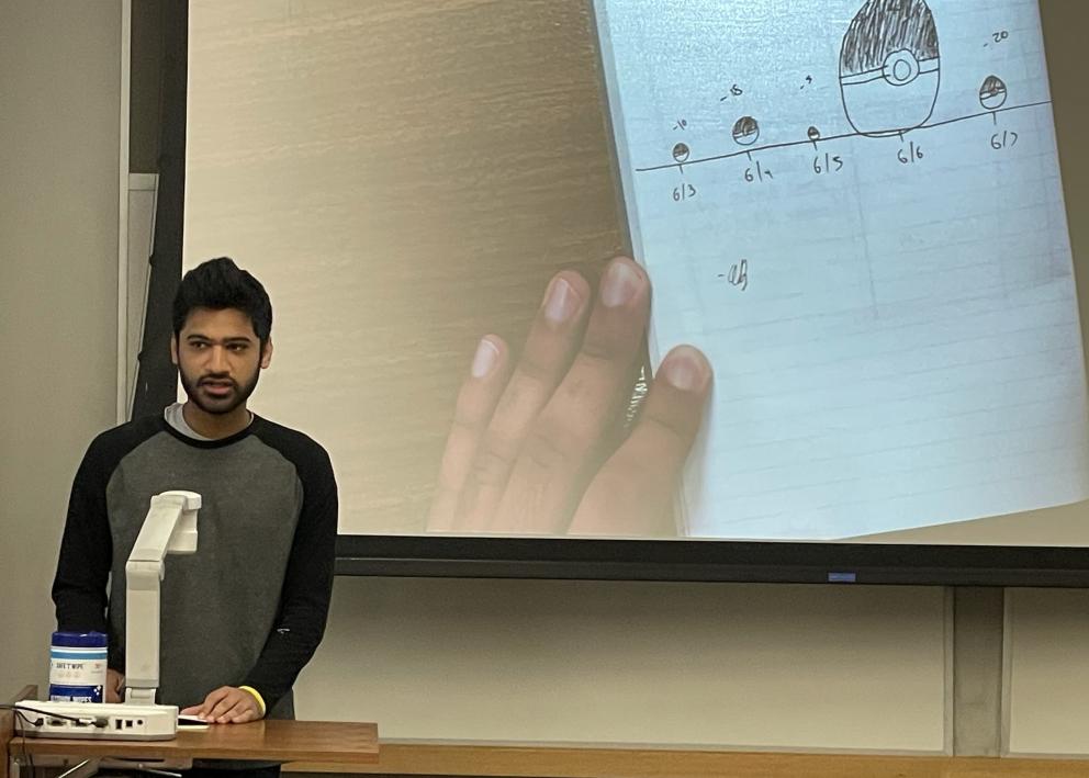 Student explaining their artistic drawing for scale using Pokemon balls