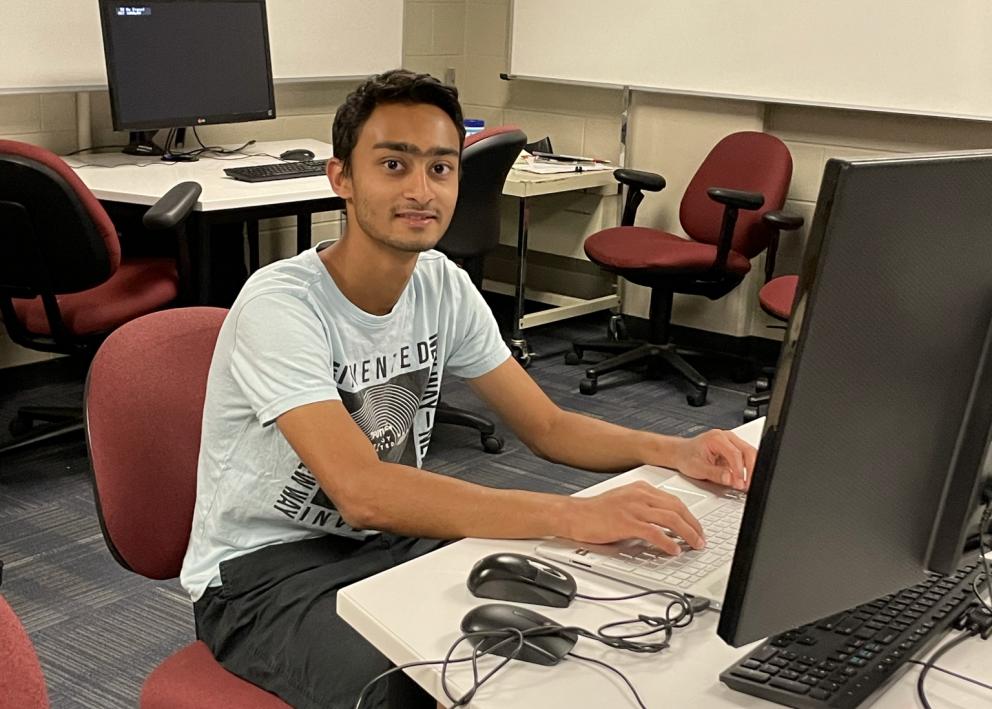 Student smiling and working at computer station
