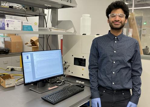 REU student Abdul standing next to computer analyzing data on the screen