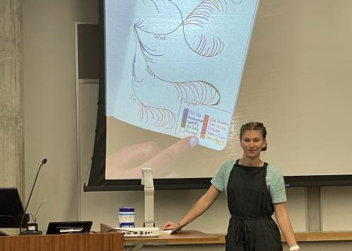 Student describing their artistic drawing to explain the scale of a concept