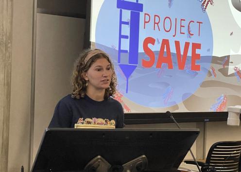 Student presenting with powerpoint slide in background showing project SAVE