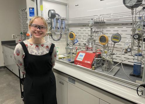  Student pictured next to a fume hood containing experimental setup
