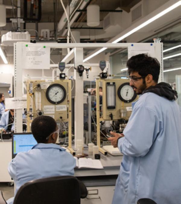 two researchers talking in a lab with equipment in the background