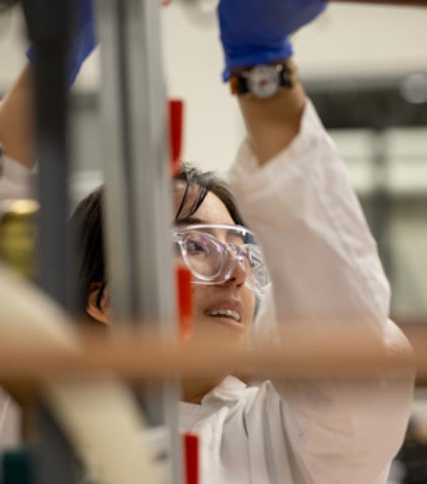A researcher reaches up for something in a lab